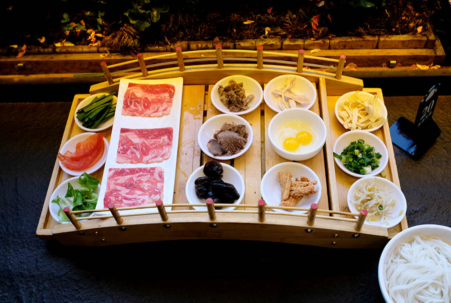 เส้นหมี่ข้ามสะพานในซุปมะเขือเทศ ร้านก๋วยเตี๋ยวข้ามสะพาน ZhaZha Mi Xian เมืองเก่าลี่เจียง มณฑลยูนนาน ประเทศจีน Beef Tomato Crossing Bridge Noodles at ZhaZha Mi Xian restaurant Lijiang old town, Yunnan province, China