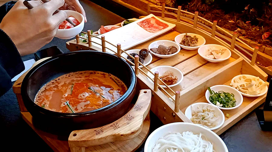 เส้นหมี่ข้ามสะพานในซุปมะเขือเทศ ร้านก๋วยเตี๋ยวข้ามสะพาน ZhaZha Mi Xian เมืองเก่าลี่เจียง มณฑลยูนนาน ประเทศจีน Beef Tomato Crossing Bridge Noodles at ZhaZha Mi Xian restaurant Lijiang old town, Yunnan province, China